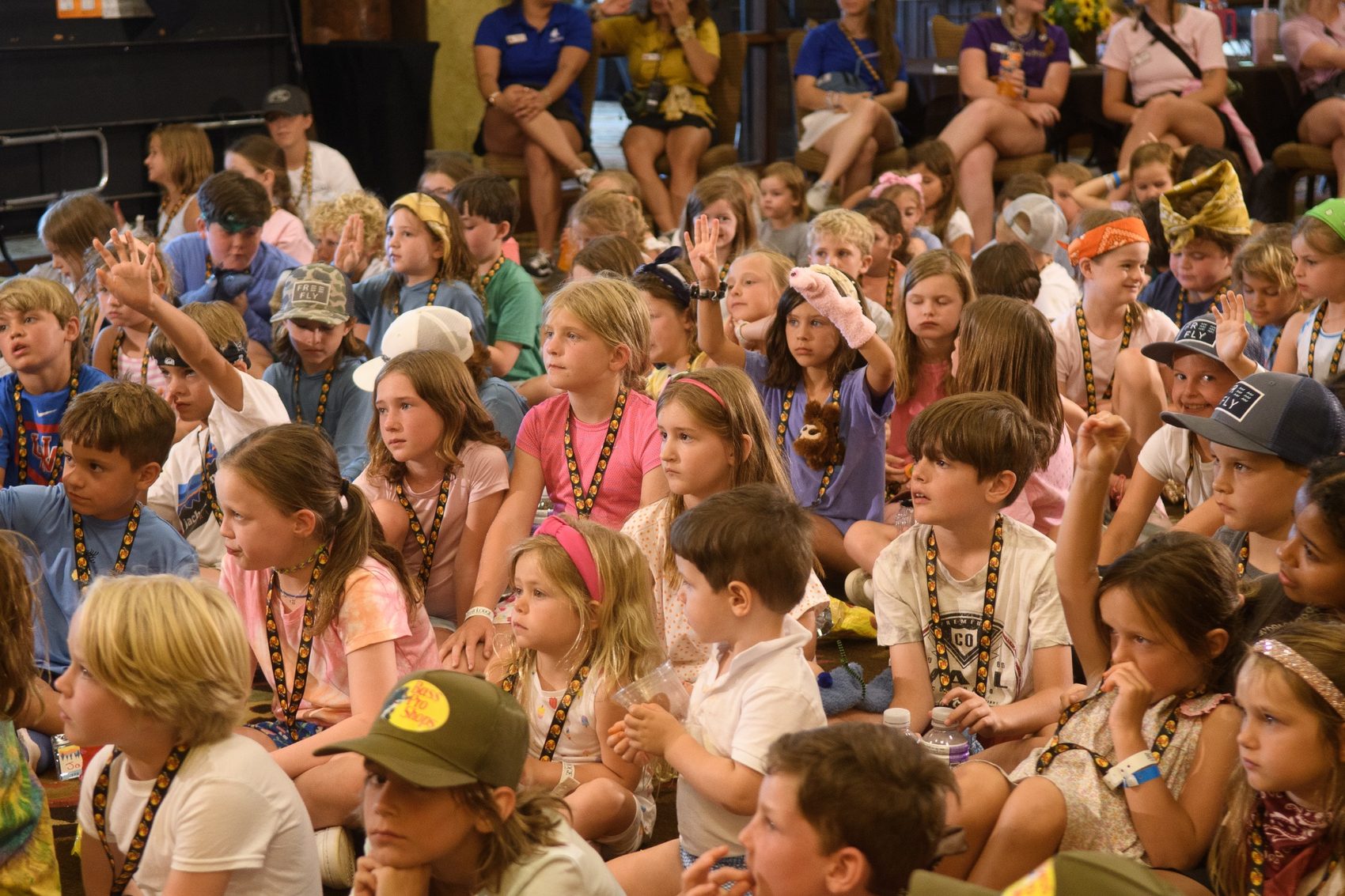 A room full of children watching a live storytelling performance, hands raised