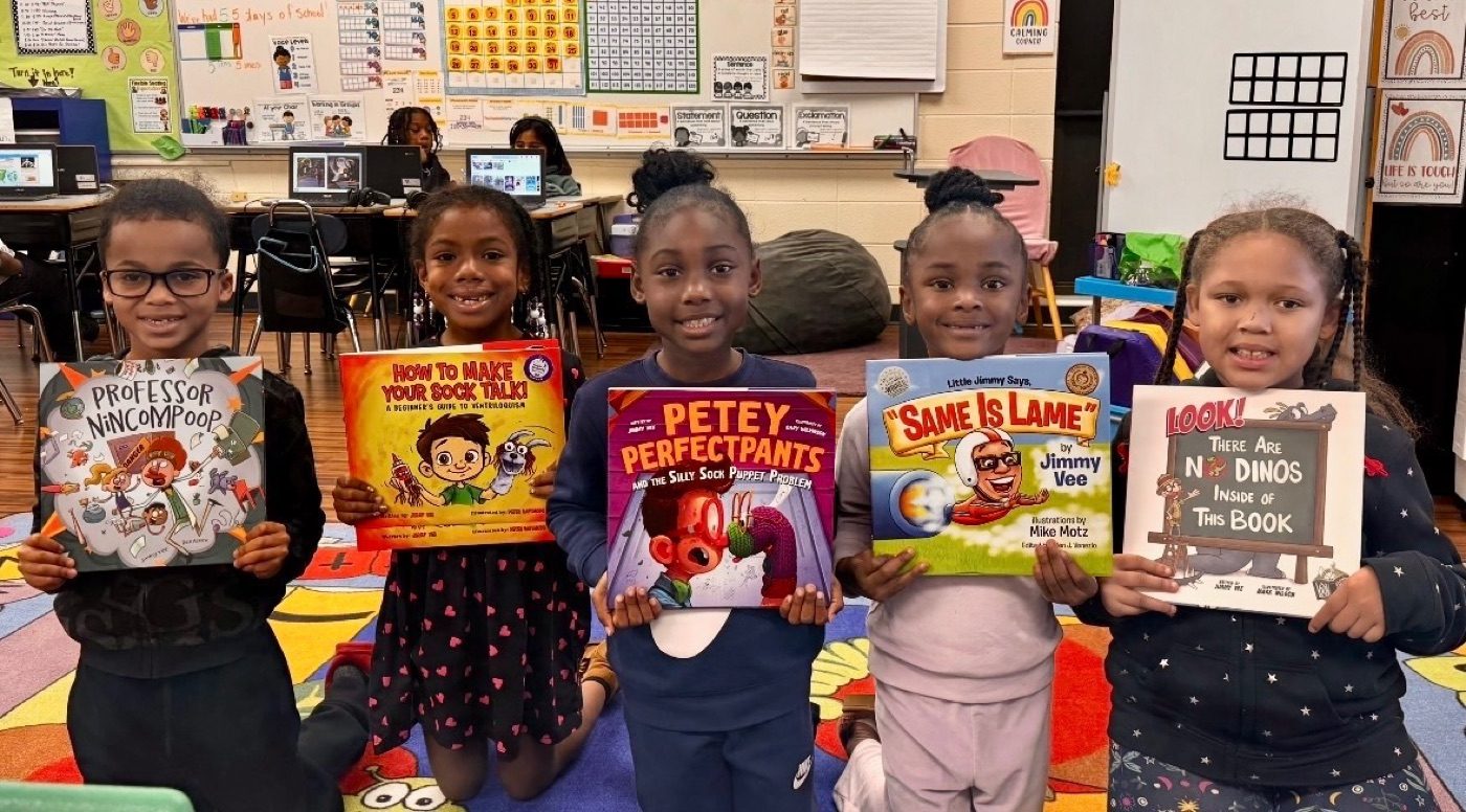 Five students in a classroom each holding up a Belly Laugh Books picture book